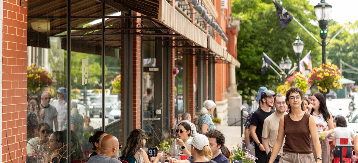 Diners and passersby at outdoor cafe tables in downtown Lee